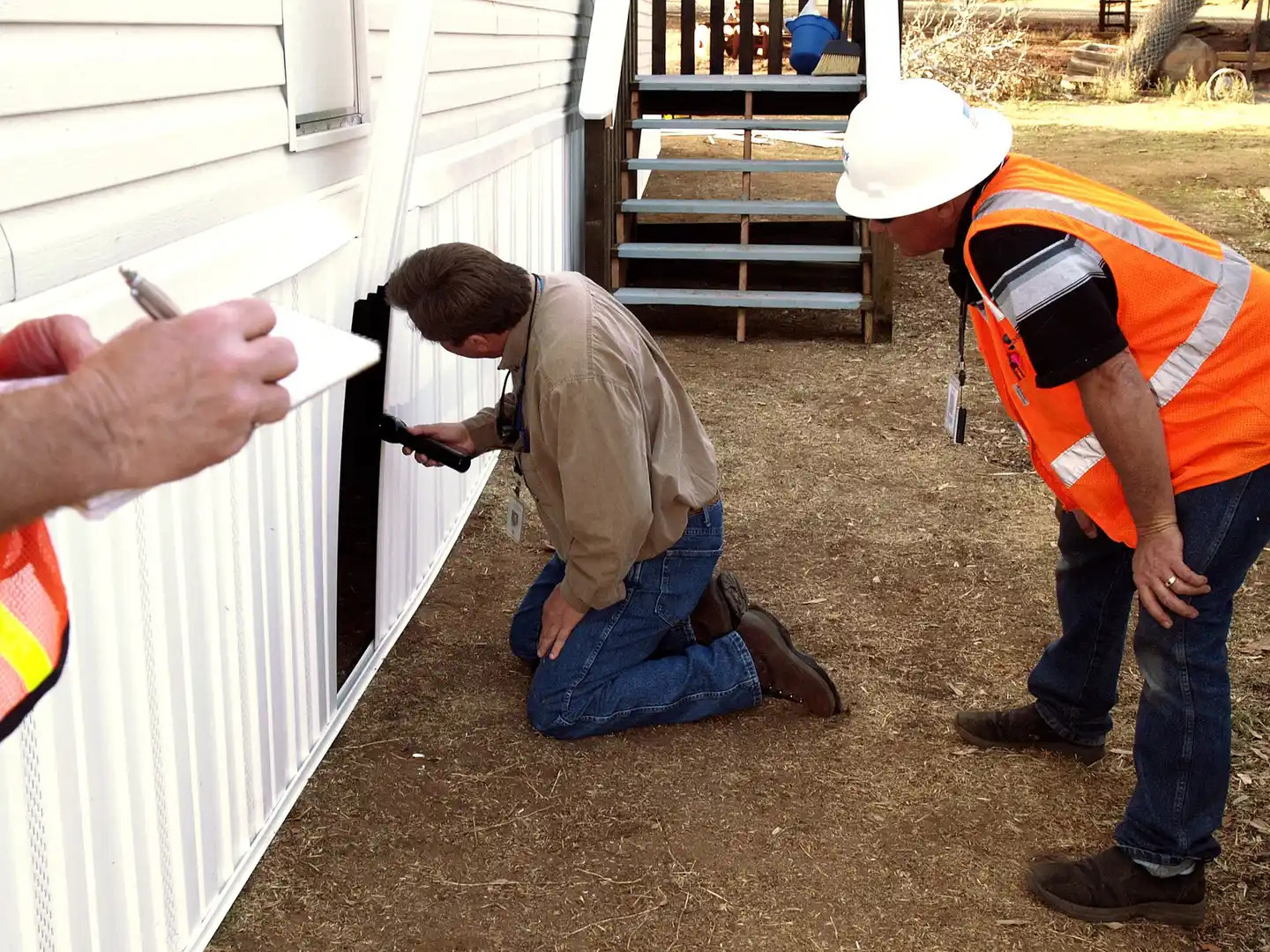 Inspectors examining a home exterior, the property review Tallahassee, FL buyers pair with a tree assessment