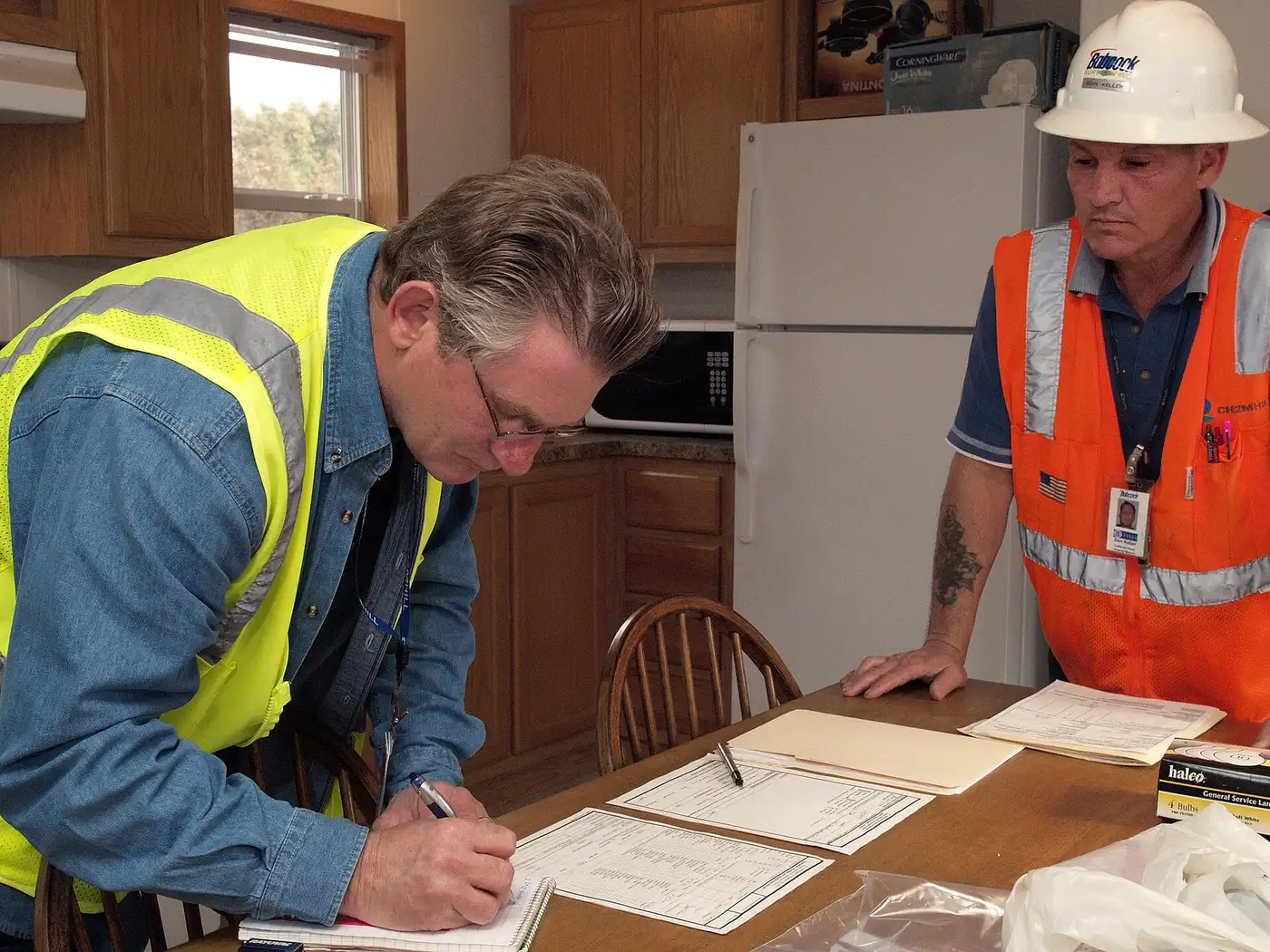 Tree Service License Requirements in Florida — How to Verify - Tallahassee Tree Service Workers in high-visibility gear reviewing credential paperwork, the license and insurance verification step for tree work in Tallahassee, FL